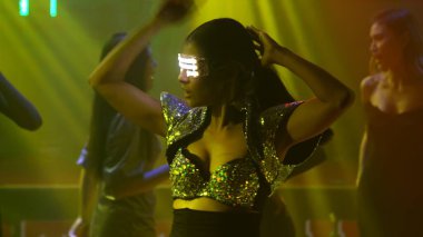 Bir grup insan disko gece kulübünde DJ 'in sahnede çaldığı müzikle dans ediyor.