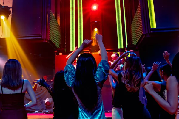 Grupo de personas bailan en discoteca al ritmo de la música de DJ en el escenario — Foto de Stock