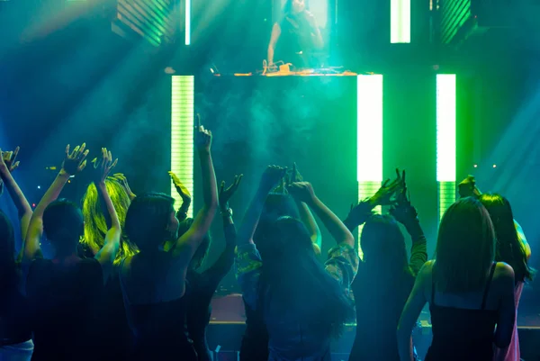 Silhouet beeld van mensen dansen in disco nachtclub op muziek van DJ op het podium — Stockfoto