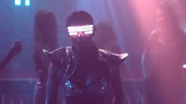 Bir grup insan disko gece kulübünde DJ 'in sahnede çaldığı müzikle dans ediyor.