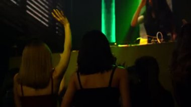Bir grup insan disko gece kulübünde DJ 'in sahnede çaldığı müzikle dans ediyor.