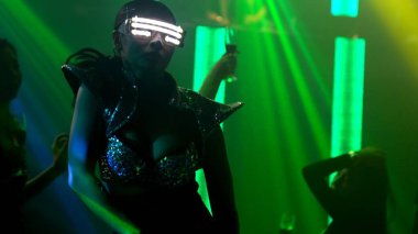 Bir grup insan disko gece kulübünde DJ 'in sahnede çaldığı müzikle dans ediyor.