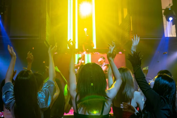 Grupo de personas bailan en discoteca al ritmo de la música de DJ en el escenario — Foto de Stock