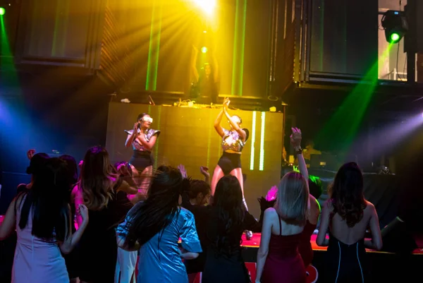 Groep mensen dansen in disco nachtclub op de beat van muziek van DJ op het podium — Stockfoto