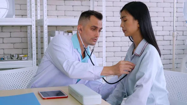 Doutor em uniforme profissional examinando paciente no hospital — Fotografia de Stock