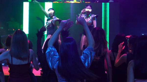 Grupo de pessoas dançam em discoteca à batida de música de DJ no palco — Fotografia de Stock