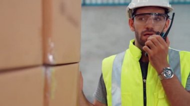 Profesyonel kargo işçisi başka bir işçiyle bağlantı kurmak için telsizle konuşuyor.