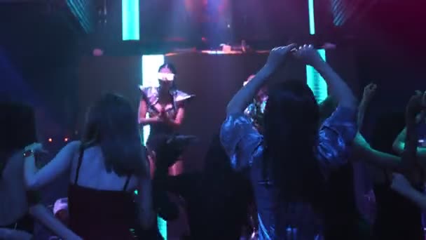 Grupo de personas bailan en discoteca al ritmo de la música de DJ en el escenario — Vídeo de stock