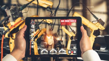 Mühendis, artırılmış gerçeklik endüstrisi teknolojisiyle robotik kolları kontrol ediyor.