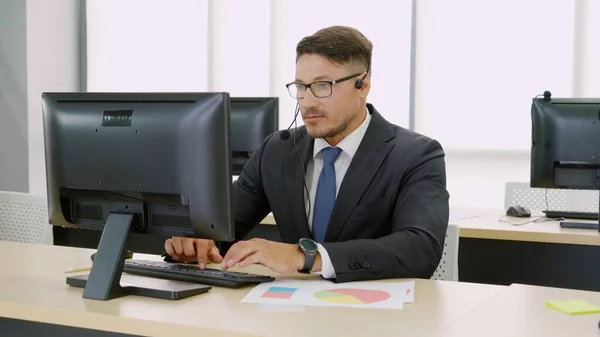 オフィスで働くヘッドセットを身に着けているビジネスマン — ストック写真