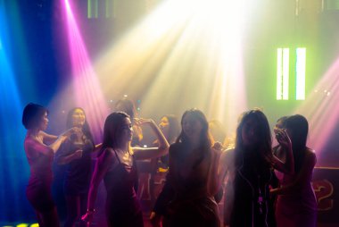 Disko gece kulübünde DJ 'in sahnede yaptığı müzikle dans eden insanların silueti.