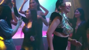 Bir grup insan disko gece kulübünde DJ 'in sahnede çaldığı müzikle dans ediyor.