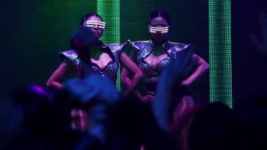 Bir grup insan disko gece kulübünde DJ 'in sahnede çaldığı müzikle dans ediyor.