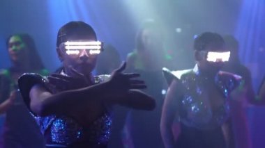 Bir grup insan disko gece kulübünde DJ 'in sahnede çaldığı müzikle dans ediyor.