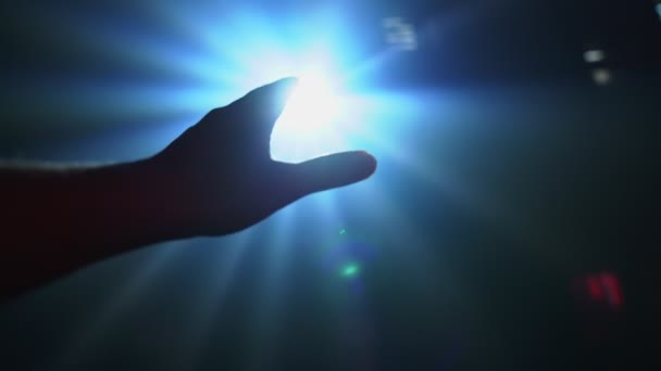 Рука тягнеться, щоб покрити сяючий прожектор — стокове відео