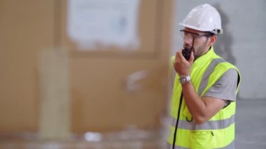 Profesyonel kargo işçisi başka bir işçiyle bağlantı kurmak için telsizle konuşuyor.