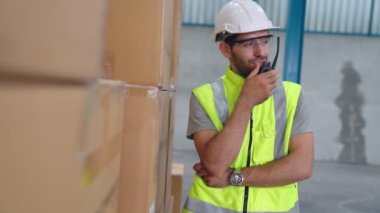 Profesyonel kargo işçisi başka bir işçiyle bağlantı kurmak için telsizle konuşuyor.