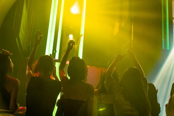 Silhouet beeld van mensen dansen in disco nachtclub op muziek van DJ op het podium — Stockfoto