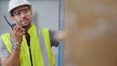 Profesyonel kargo işçisi başka bir işçiyle bağlantı kurmak için telsizle konuşuyor.