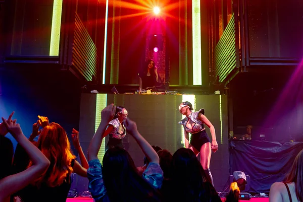 Groep mensen dansen in disco nachtclub op de beat van muziek van DJ op het podium — Stockfoto