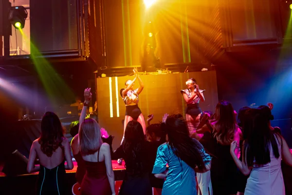 Groep mensen dansen in disco nachtclub op de beat van muziek van DJ op het podium — Stockfoto