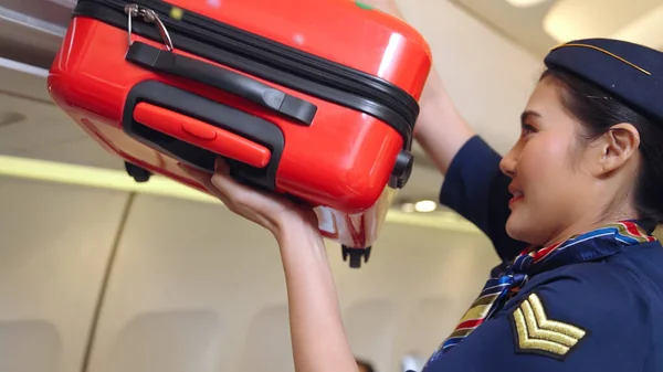 Tripulação de cabine levantar saco de bagagem no avião — Fotografia de Stock