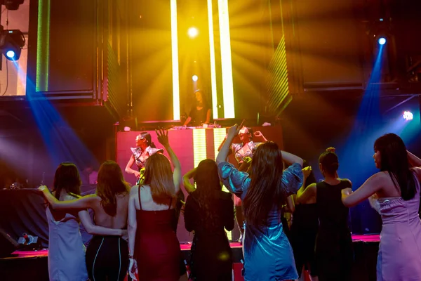 Grupo de personas bailan en discoteca al ritmo de la música de DJ en el escenario — Foto de Stock