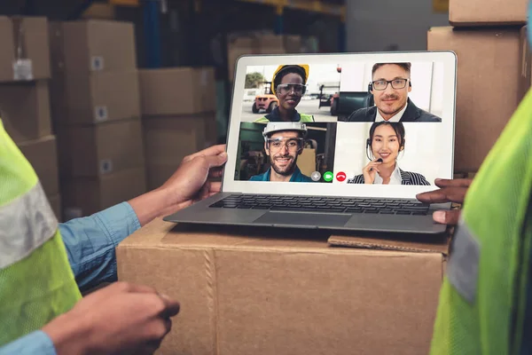 Warehouse staff talking on video call at computer screen in storage warehouse