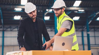 Fabrikada çalışan ve üretim planını tartışan iki fabrika işçisi. .