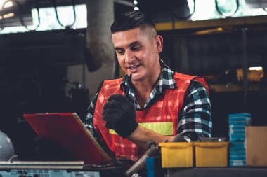 Fabrika işçisi, makine parçalarını incelerken taşınabilir radyodan konuşuyor.