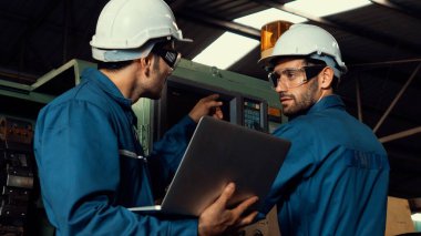 Bir grup yetenekli fabrika işçisi atölyede makine ekipmanı kullanıyor.