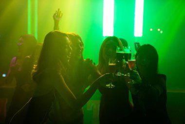 Disko gece kulübünde DJ 'in sahnede yaptığı müzikle dans eden insanların silueti.
