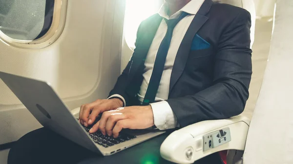 Молодой бизнесмен использует ноутбук в самолете — стоковое фото