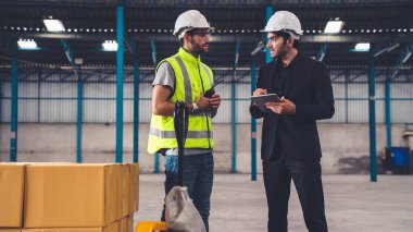 Fabrikada çalışan ve üretim planını tartışan iki fabrika işçisi. .