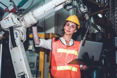 Akıllı fabrika işçisi imalat atölyesinde robot kolu kontrol ediyor.