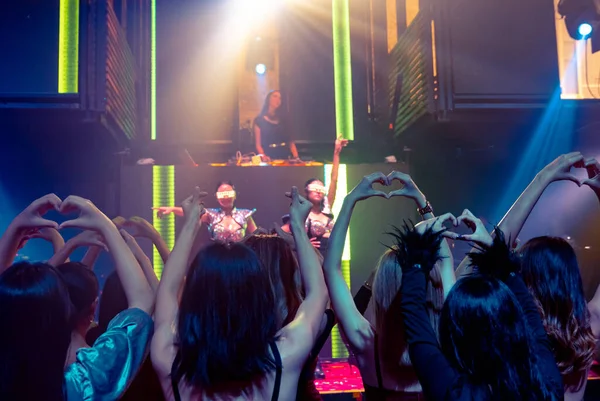 Grupo de personas bailan en discoteca al ritmo de la música de DJ en el escenario —  Fotos de Stock