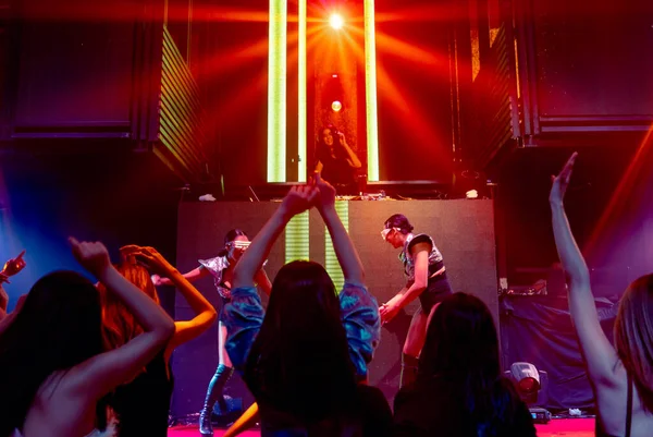 Grupo de personas bailan en discoteca al ritmo de la música de DJ en el escenario — Foto de Stock