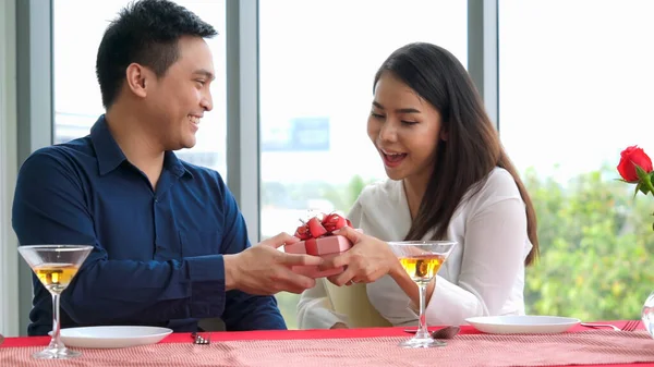 Romantic couple giving gift to lover at restaurant — Stock Photo, Image