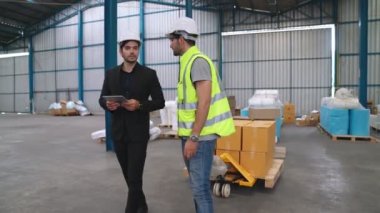 Fabrika işçileri depodaki bir yük arabasında kutu teslimatı yapıyor. .