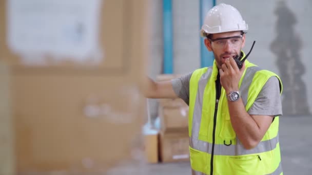 Professional cargo worker talks on portable radio to contact another worker — Stock Video