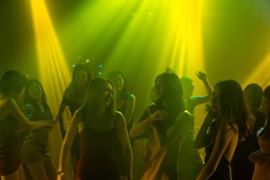 Disko gece kulübünde DJ 'in sahnede yaptığı müzikle dans eden insanların silueti.