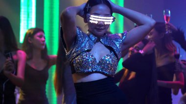 Bir grup insan disko gece kulübünde DJ 'in sahnede çaldığı müzikle dans ediyor.