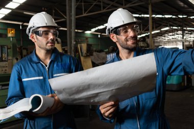 Bir grup yetenekli fabrika işçisi atölyede makine ekipmanı kullanıyor.