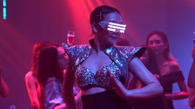 Bir grup insan disko gece kulübünde DJ 'in sahnede çaldığı müzikle dans ediyor.