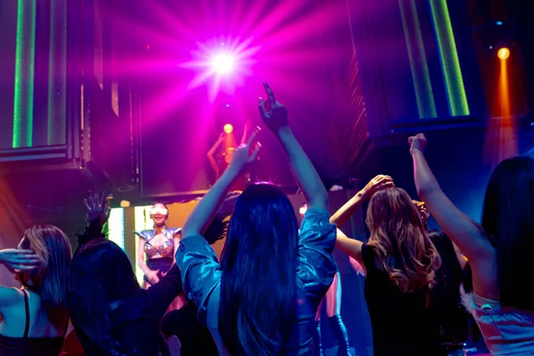 Grupo de personas bailan en discoteca al ritmo de la música de DJ en el escenario — Foto de Stock