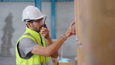 Profesyonel kargo işçisi başka bir işçiyle bağlantı kurmak için telsizle konuşuyor.