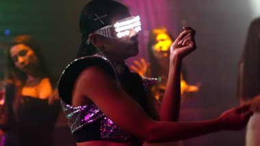 Bir grup insan disko gece kulübünde DJ 'in sahnede çaldığı müzikle dans ediyor.