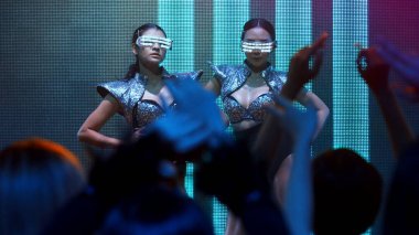 Bir grup insan disko gece kulübünde DJ 'in sahnede çaldığı müzikle dans ediyor.