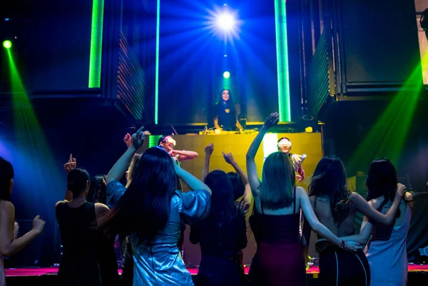 Grupo de personas bailan en discoteca al ritmo de la música de DJ en el escenario — Foto de Stock