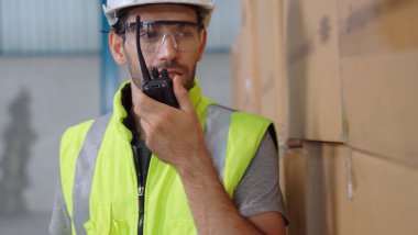 Profesyonel kargo işçisi başka bir işçiyle bağlantı kurmak için telsizle konuşuyor.